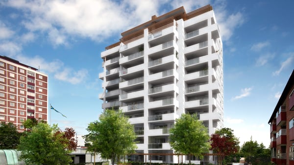 Vit bostadshus med balkonger och gröna träd utanför