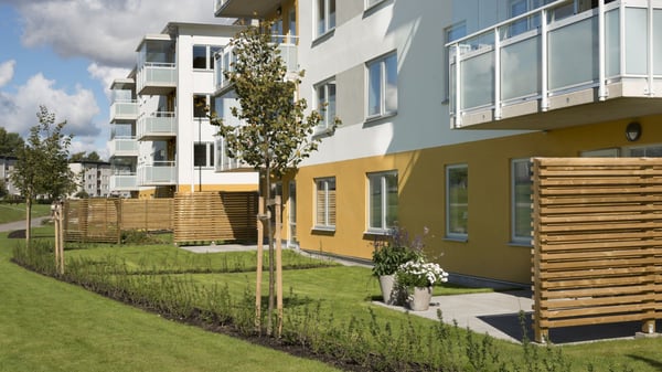 Inflyttningsklar lägenhet i bostadshus med balkonger, grön innergård och träskärmar