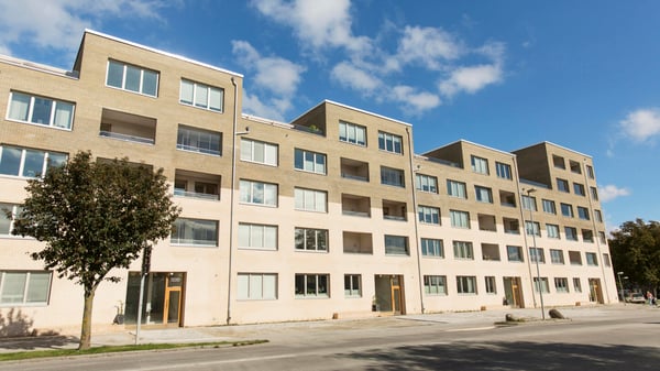 Inflyttningsklar lägenhet i modern flerbostadsbyggnad med ljus fasad och stora fönster under blå himmel