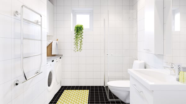 Ljust badrum med tvättmaskin, dusch, toalett och handfat i en lägenhet