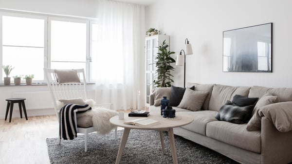 Ljust och stilrent vardagsrum med soffa, fåtölj, soffbord och stora fönster