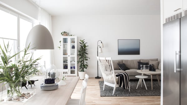 Ljust och modernt vardagsrum med kök, soffa, matplats och stora fönster