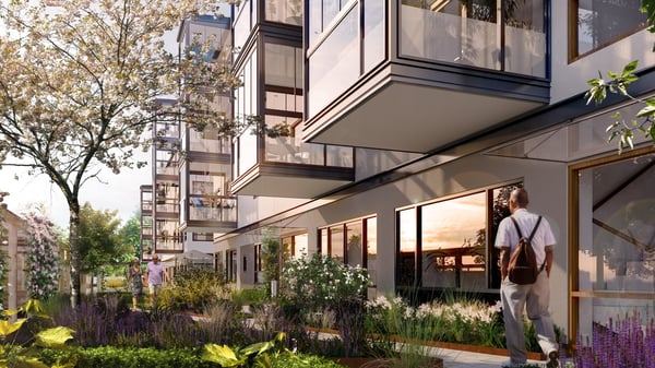 Nyproducerade lägenheter med stora fönster, balkonger och grön innergård. Personer promenerar längs gångvägen utanför bostadshuset