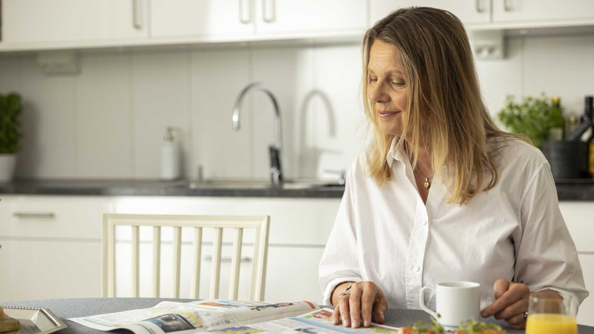 Kvinna läser tidning vid frukostbord