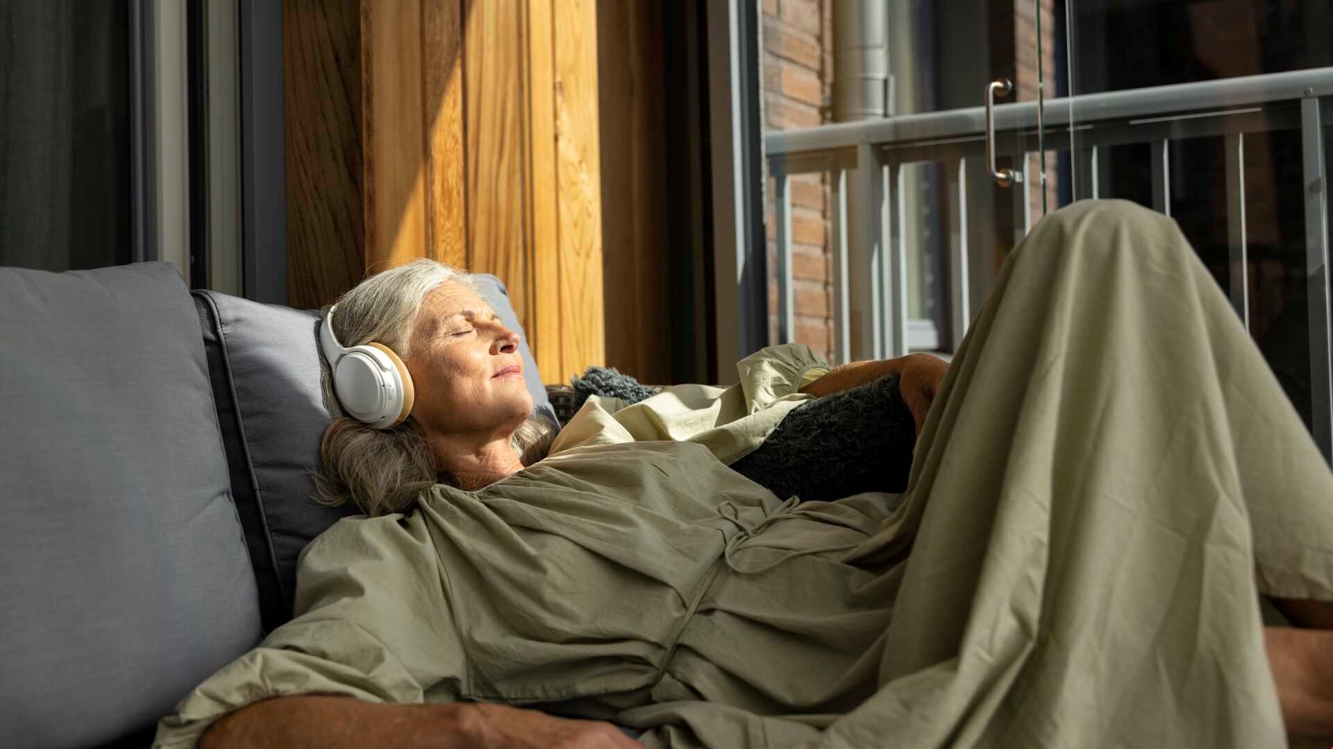 Kvinna med hörlurar vilar på balkong